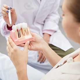 Dentist pointing to model of dental implant