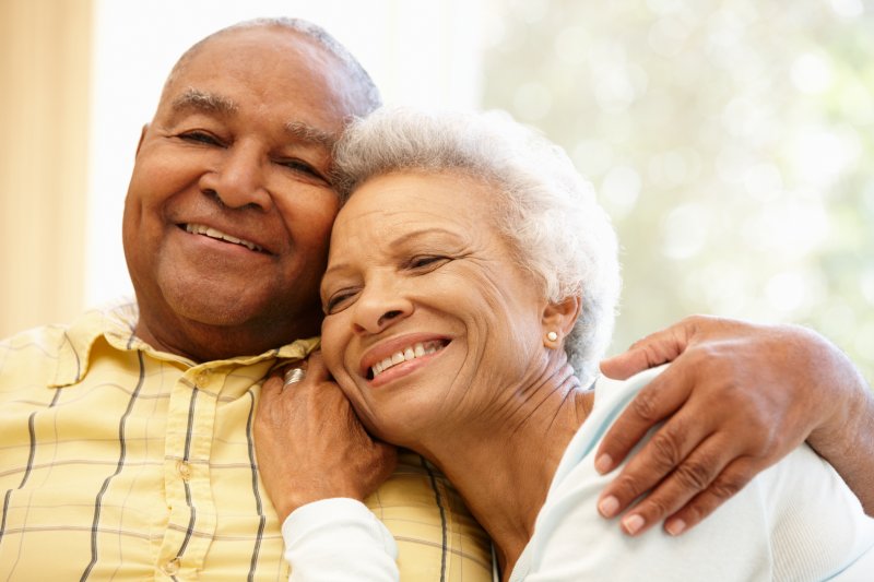 older couple with dentures smiling and embracing